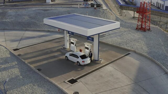 A gas station with a white sedan being refueled from above during drone filming.