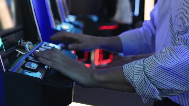 A man is playing slots machine and roulette or poker, gambling in casino close up, game machine in cafe or hotel lobby. Playing betting game.