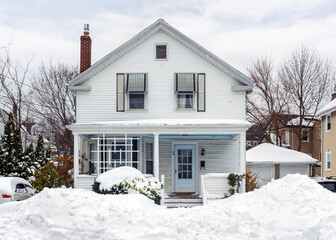 Traditional white New England house stands behind massive snowbanks after a winter storm in Greater Boston area, Massachusetts © Baharlou