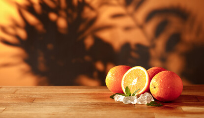 Cold orange fruit on a rustic wooden table with soft, moody lighting. Blurred background and warm interior and a wall with subtle leaf shadows, creating a cozy and elegant atmosphere. © magdal3na
