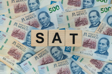 Obraz premium SAT In Mexico, an abbreviation for personal income tax. A financial concept. Taxes in Mexico, written on wooden blocks, Mexican pesos, business background. Close up