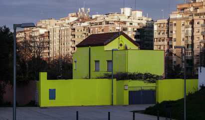 Obraz premium Urban Standout: Unique lime green house architecture set against traditional apartment blocks.