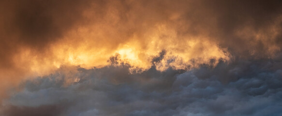 Dramatic clouds at sunset with golden glow contrast of dark and light tones atmospheric sky landscape © Larysa