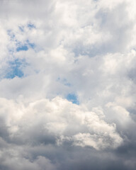 Fototapeta premium Dense white and gray clouds in sky with patches of blue dramatic cloudscape natural light atmospheric background