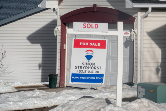 Calgary, Alberta, Canada. March 19, 2026. A RE/MAX Real Estate Sign With a Sold Sticker Displayed in Front of a Residential House in Winter.