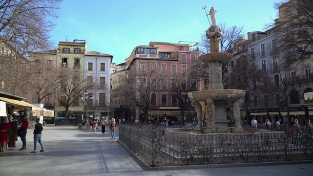 Bib Rambla central square of Granada, Andalusia, Spain in spring, classic building facades glowing in warm sunlight as cool shadow falls across the plaza under a beaut