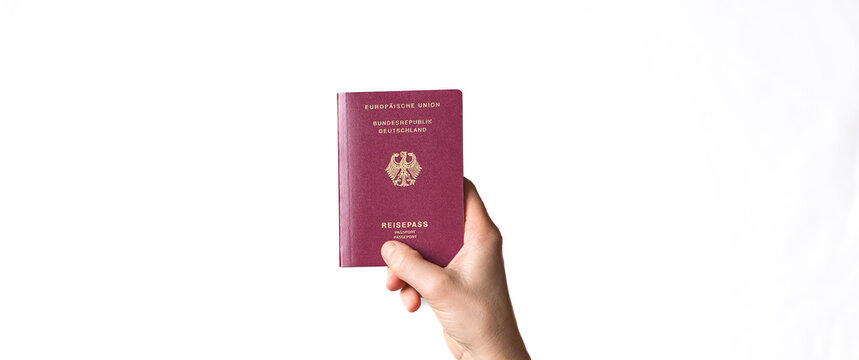 Person's hand holding a red German passport with golden eagle emblem against a clean white background