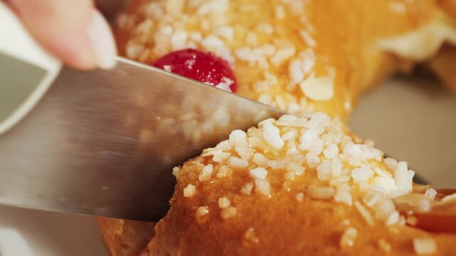 Roscon de reyes. A round cake baked from a rich yeast dough and decorated with sugar, almonds, and glazed fruit. Cutting a piece of cake with a knife. High quality 4k footage