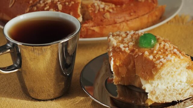 Cake Roscon de reyes with cup of black tea on the table. A traditional pastry prepared and served on the Feast of the Three Kings or Epiphany in Spain. High quality 4k footage