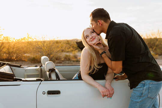 Couple kissing in convertible in desert