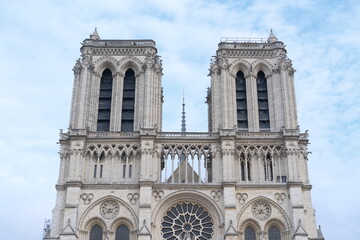 Fototapeta premium Front facade of Notre Dame de Paris on blue sky background. Traveling to Europe, sightseeing, visiting important religious places. Notre-Dame Cathedral in France