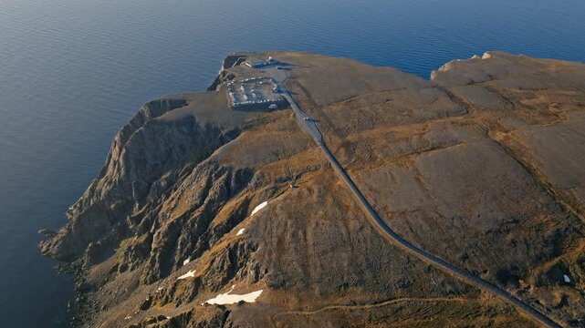 Drone aerial flying toward the Nordkapp plateau and coastal cliffs in northern Norway. Arctic tundra landscape rises above the Barents Sea.