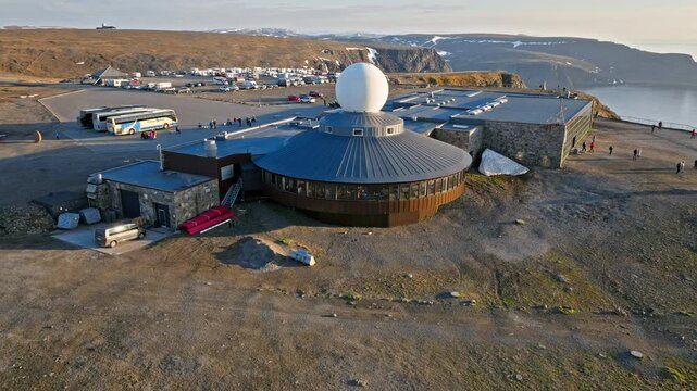Aerial view circling the Nordkapp visitor complex and parking area on Mageroya Island, Norway. Remote Arctic plateau overlooks the Barents Sea.