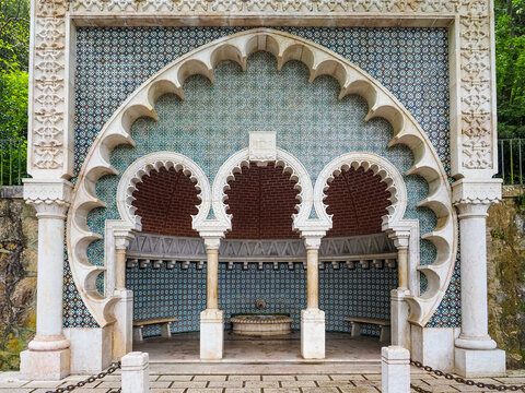 Ancient public source of drinking water on the street in Sintra, Portugal. The source is framed by ornate concrete structure with Portuguese glazed tiles, traditional and colorful Azulejo.