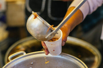 Spicy lamb consommé, being served in a disposable cup, traditional Mexican food.  © Marco