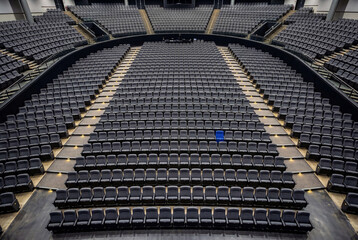 Obraz premium Empty theater seats with one blue seat in aligned rows high angle