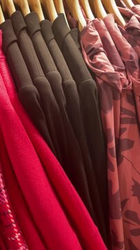 Blue red plaid coats on hangers along wooden rack, closeup of tweed and knit textures, camouflage and solid patterns alternating, neat row of jackets