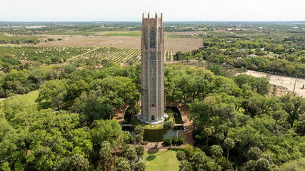 Naklejka premium A sweeping drone shot captures the iconic Bok Tower surrounded by greenery and scenic countryside in Central Florida.