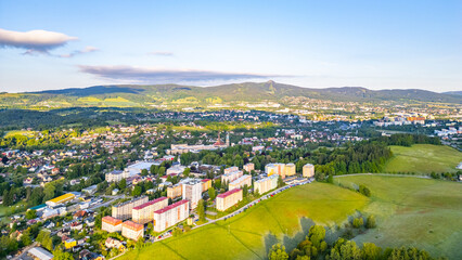 Fototapeta premium The town of Vratislavice nad Nisou in Czechia. It features buildings, green fields, and hills in the background. The scene captures a sunny day and the layout of the town.