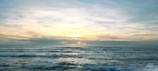 Fototapeta premium Ocean landscape. Cloudy sky at sunset. Shore with large rocks. Insertable space. Photography, wallpaper, cover, background.
