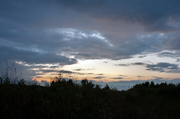 Fototapeta premium Panorama of dawn fire in the sky above the natural pasture. Golden red clouds just before sunrise. Picturesque landscape at sunrise. Beauty in nature