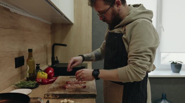 Man Seasoning Fresh Steaks on a Cutting Board, Preparing a Delicious Home-Cooked Meal
