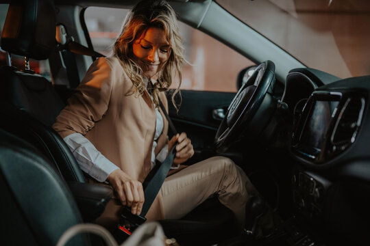 Woman buckling seatbelt in car, prioritizing road safety for daily commute and responsible driving