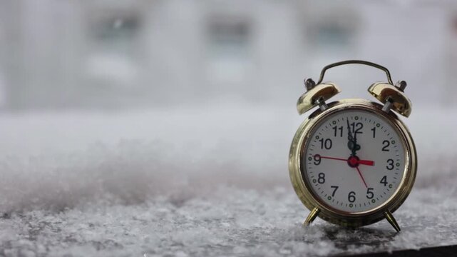 Alarm clock on a snowy winter background. Video