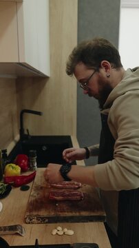 Man Seasoning Raw Beef Steaks with Fresh Pepper in a Modern Kitchen for Delicious Meal Preparation