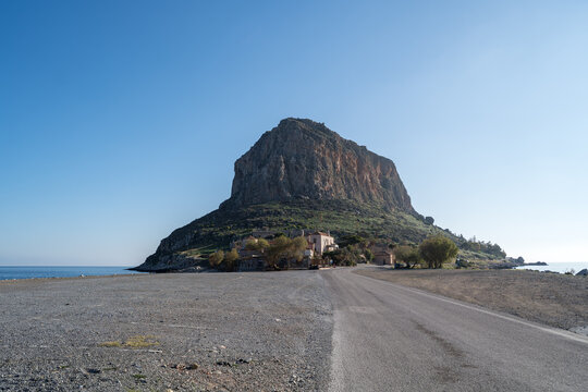 Monemvasia rock island with coastal buildings in calm sea, Laconia, Greece