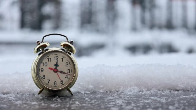 Alarm clock on a snowy winter background. Video