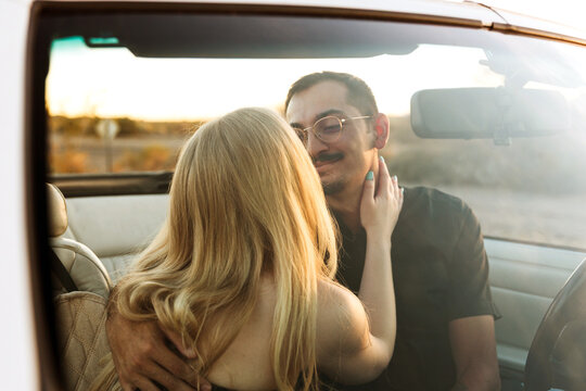 loving couple looking at each other parked in convertible car