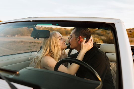 affectionate couple through convertible windshield 