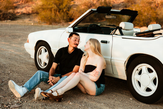 couple sitting by convertible car looking at each other