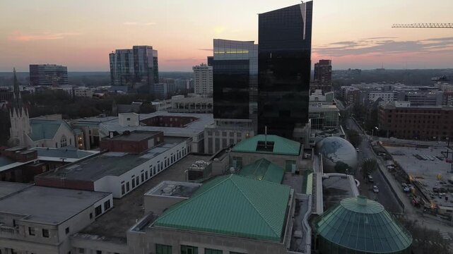 Aerial pull-back view of the museums and downtown Raleigh high rises at sunset looking West