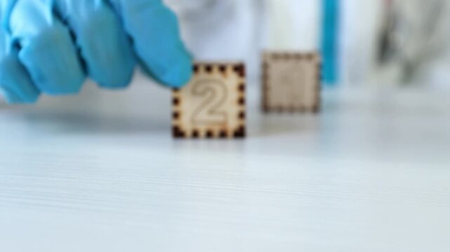 The doctor's gloved hand pushes away the wooden cubes with the number "21" on them. Video