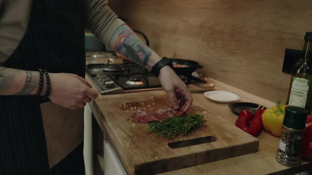 Man in Apron Places Seasoned Steak into a Hot Pan for Cooking