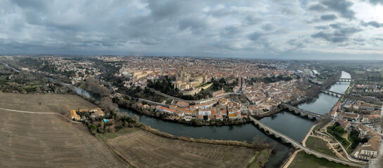 Béziers France aerial view: A masterpiece of Gothic and Romanesque architecture featuring the fortified Saint-Nazaire Cathedral bridges over the Orb river © tamas