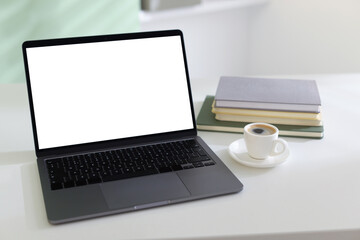 Fototapeta premium Stylish workplace with laptop, notepads and cup of coffee on white desk indoors, closeup