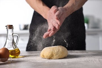 Fototapeta premium Man with dough at grey table indoors, closeup