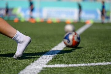 Obraz premium Soccer player kicks ball on artificial turf field during training session