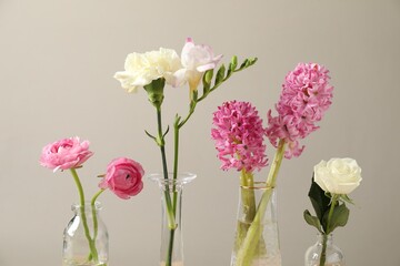 Obraz premium Beautiful flowers in vases against light background, closeup