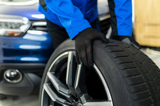 Mechanic holding car wheel tire during replacement in auto workshop