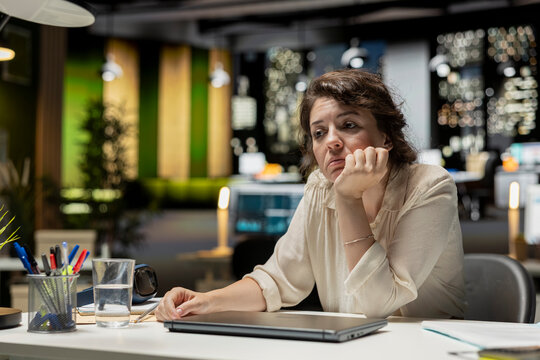 Demotivated businesswoman, sighing, pushing limits, late at night, being in a mental haze and troubled by workload and life choices. Uninterested tensed woman struggling with fatigue.