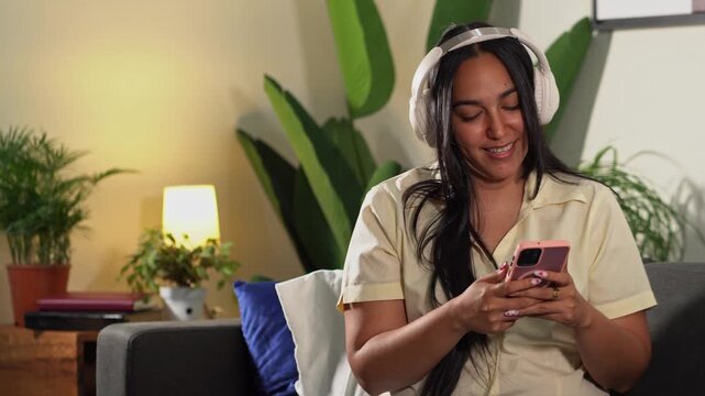 Potrait of young woman woman listening to music on headphones and using smartphone