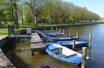 Blue rental rowing boats moored at canal dock, Netherlands © John Korf