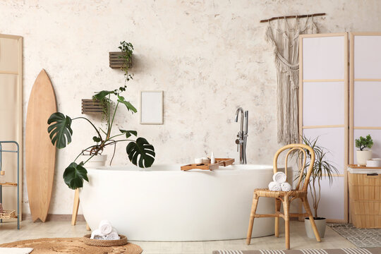 Interior of modern bathroom with bathtub, chair and folding screen