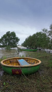 A traditional Vietnamese coracle boat sits on the shore in Hoi An, Vietnam. The boats are used by local fisherman to navigate the waterways and fish the local waters.