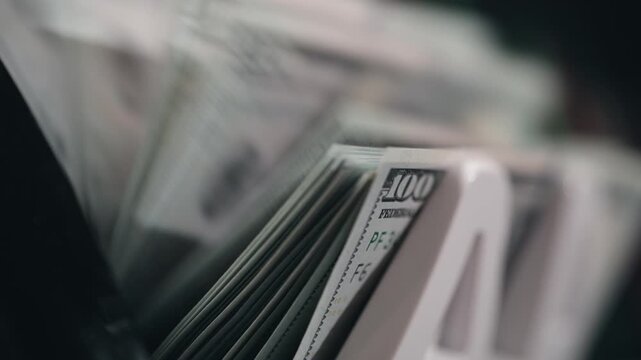 High-speed money counter counting $100 bills. Banking and cash management concept.
