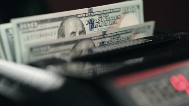 Close-up of one hundred dollar bills stacked in counting machine. Banking concept.
